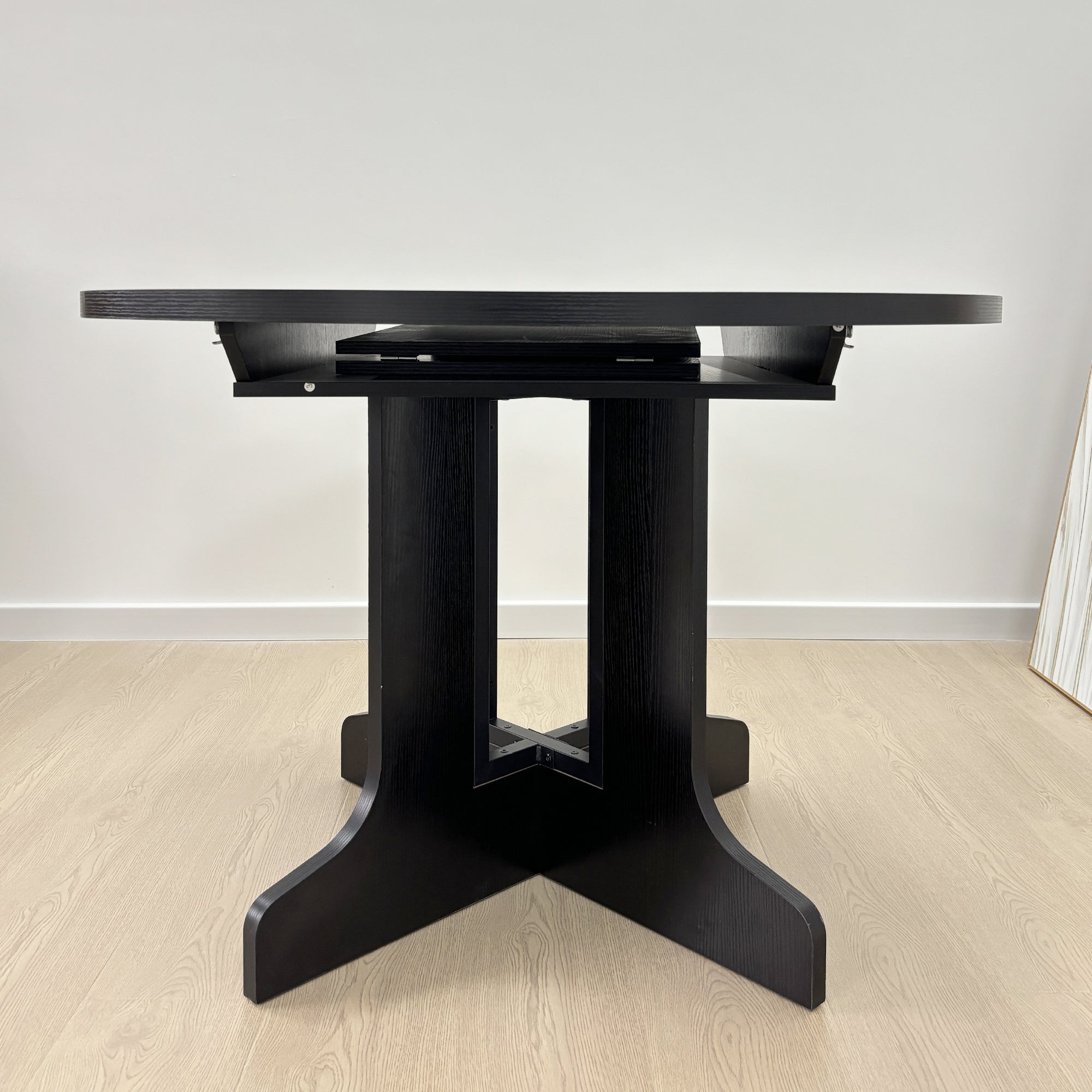 Black table partly extended showing the X-base and slide rails with the folding leaf raised