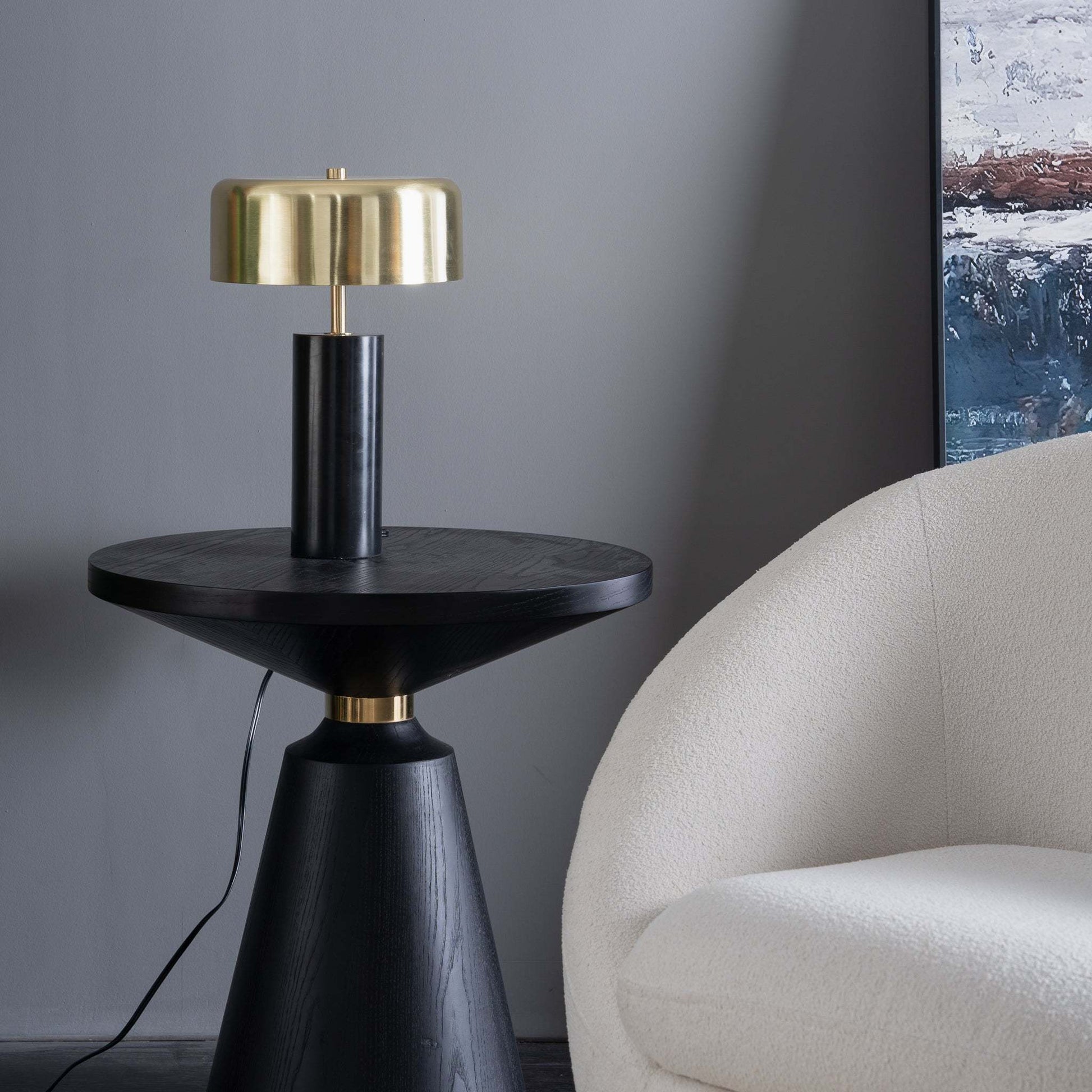 black marble base table lamp with gold shade on top of an end table next to a couch in a modern interior