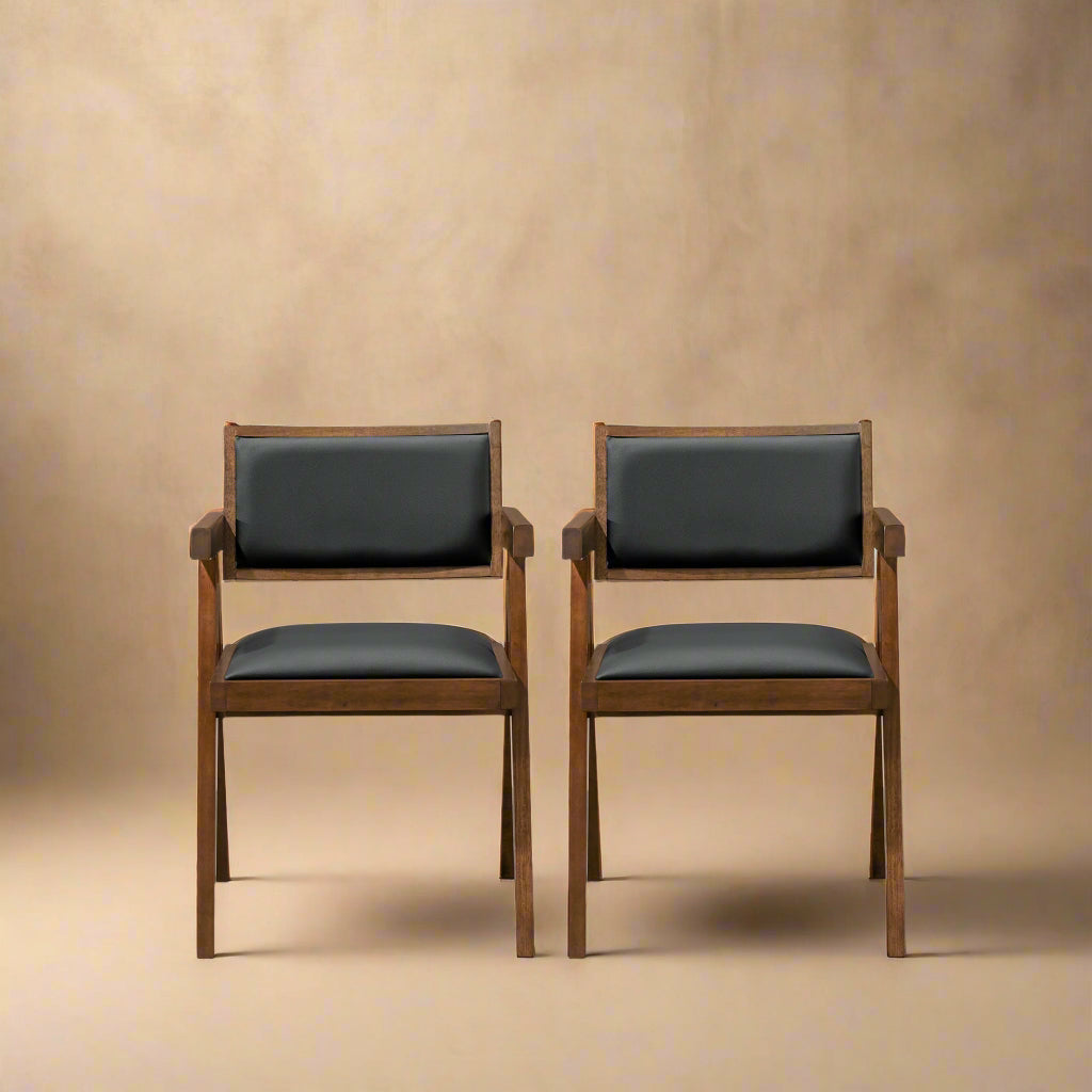 forward shot of solid wood black vegan leather dining chairs against a cream background