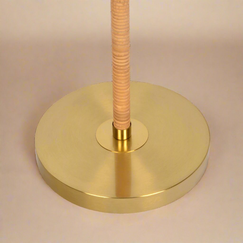 closeup of the brass base on the boho rattan floor lamp showing the gold tone and the rattan weave around the stem