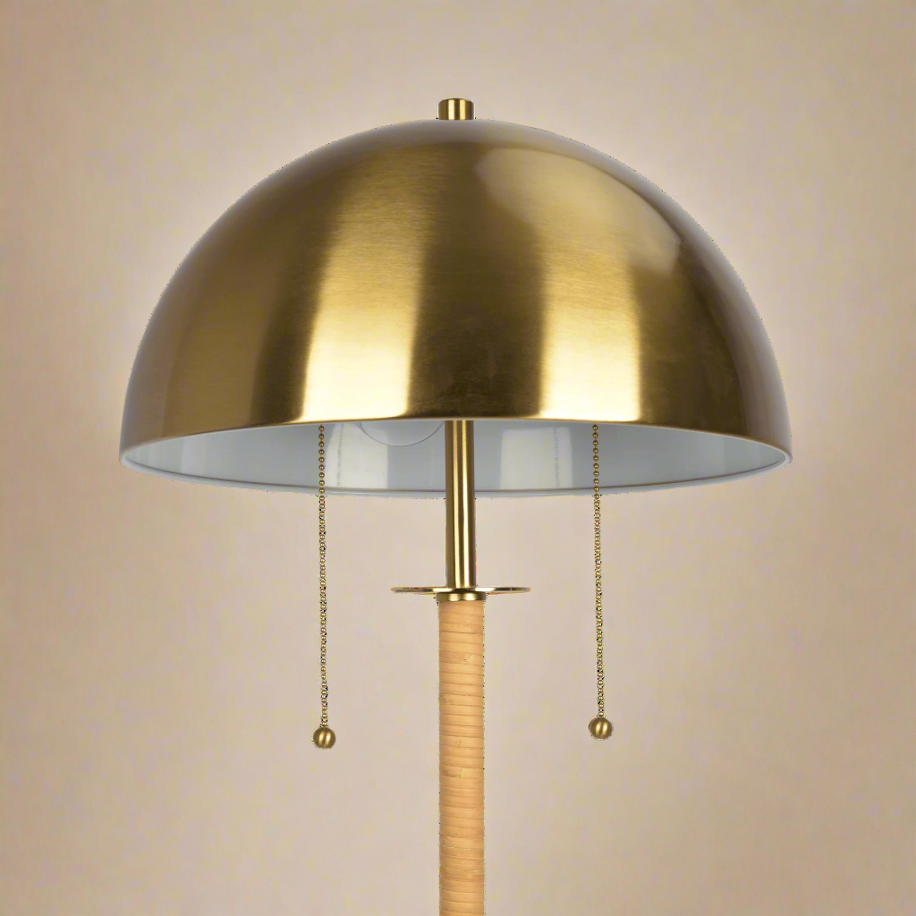 closeup of the gold dome on the boho rattan floor lamp showing the lamp strings coming out of the shade and the rattan weave around the stem