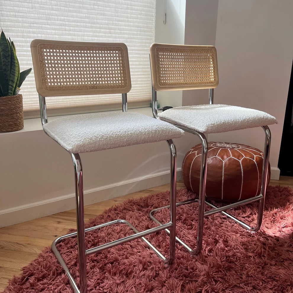 Midcentury Modern Counter Stools Set of 2 with white bouclé seat, rattan backs, and stainless steel legs in a cozy room.