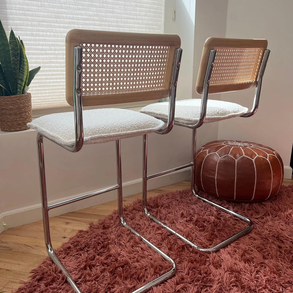 Midcentury Modern Counter Stools Set of 2 with white bouclé seats, rattan backs, and stainless steel legs in a bright room.