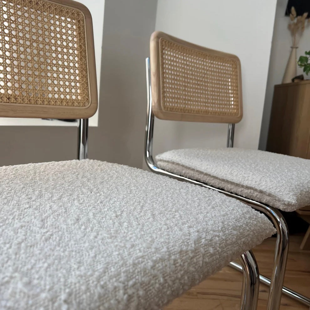 closeup of white boucle seat on mid century modern dining chairs with rattan backrests