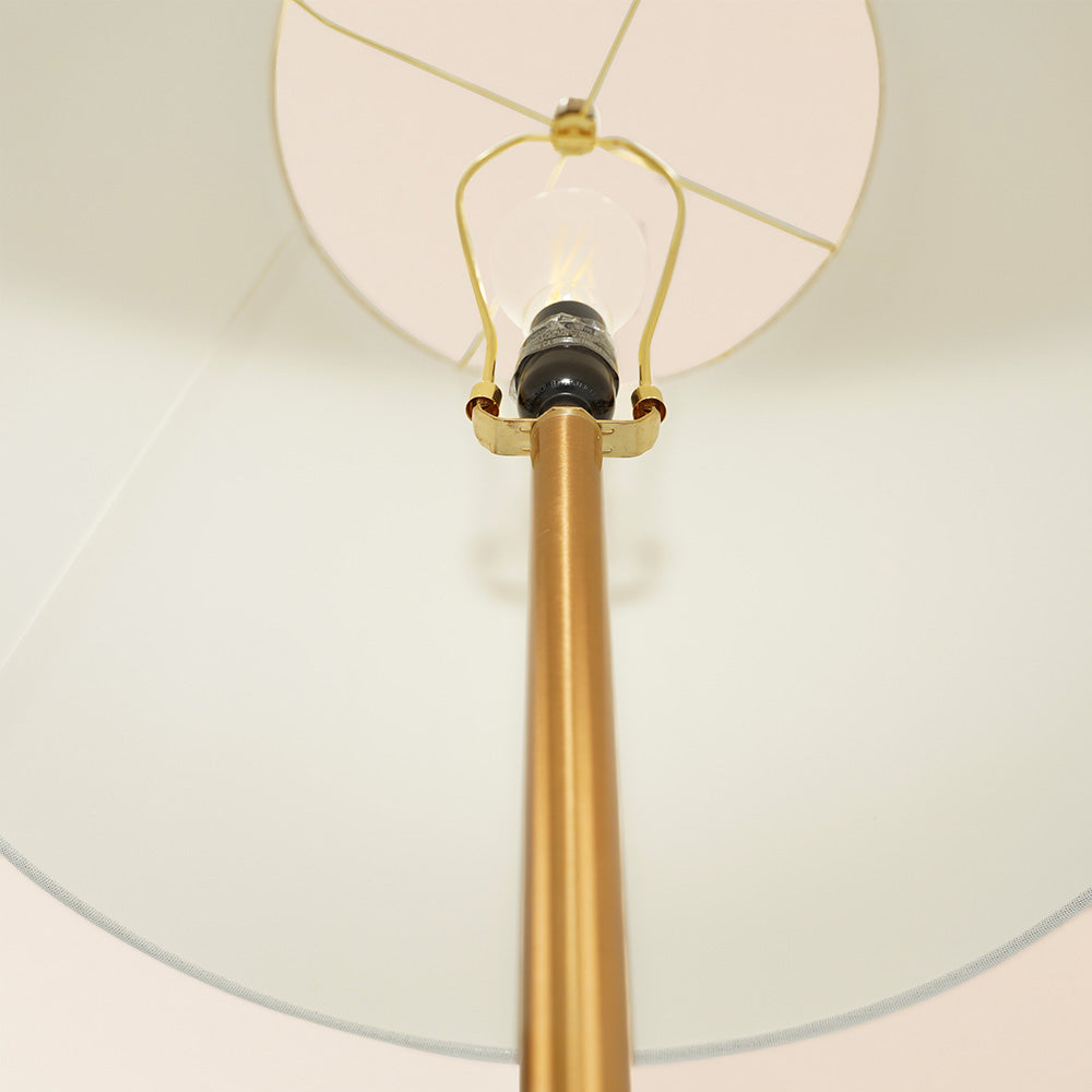 upward shot of the interior of the lampshade of a brass mid century modern floor lamp with an end table