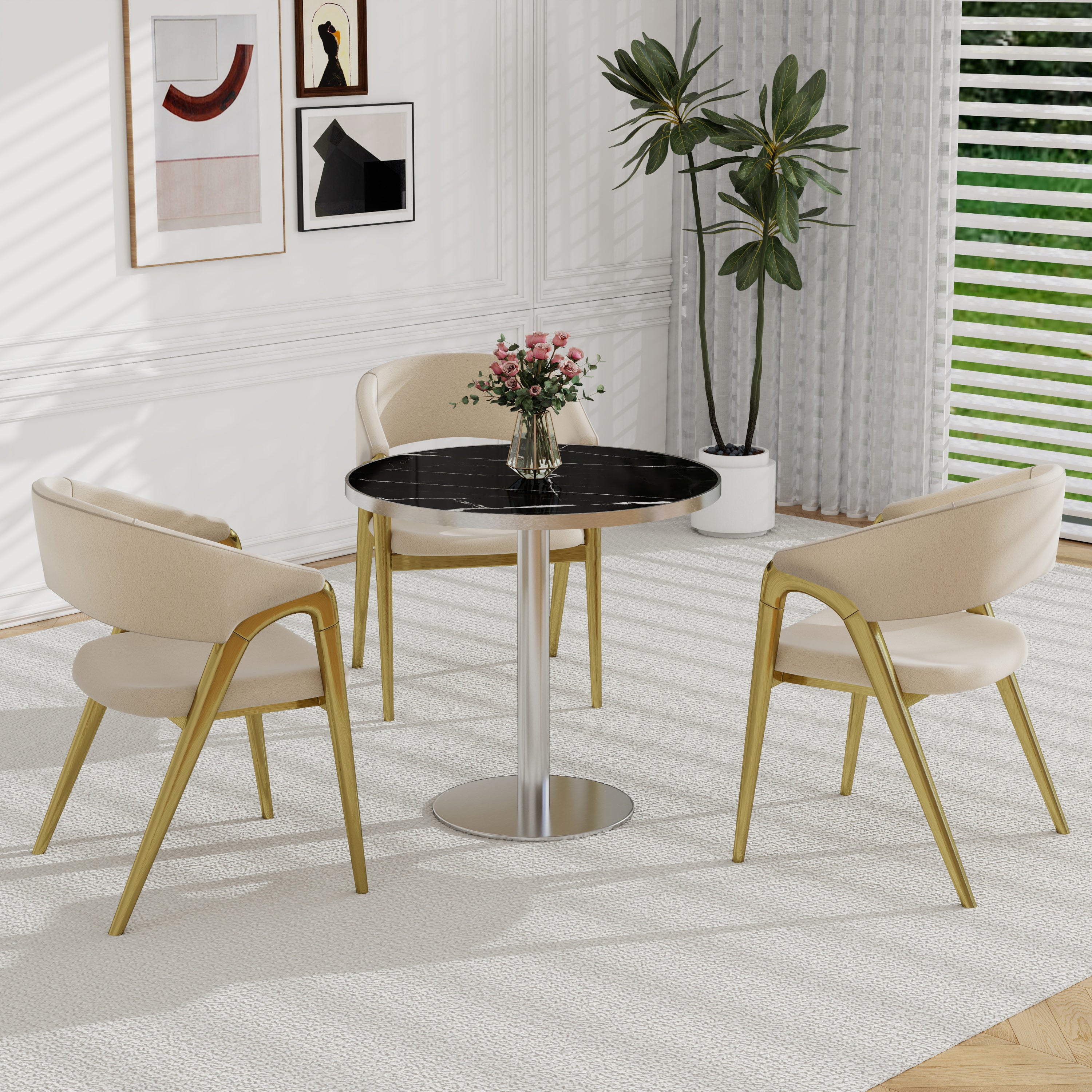 Black sintered stone round dining table with cream gold-leg chairs, gallery wall and plant behind