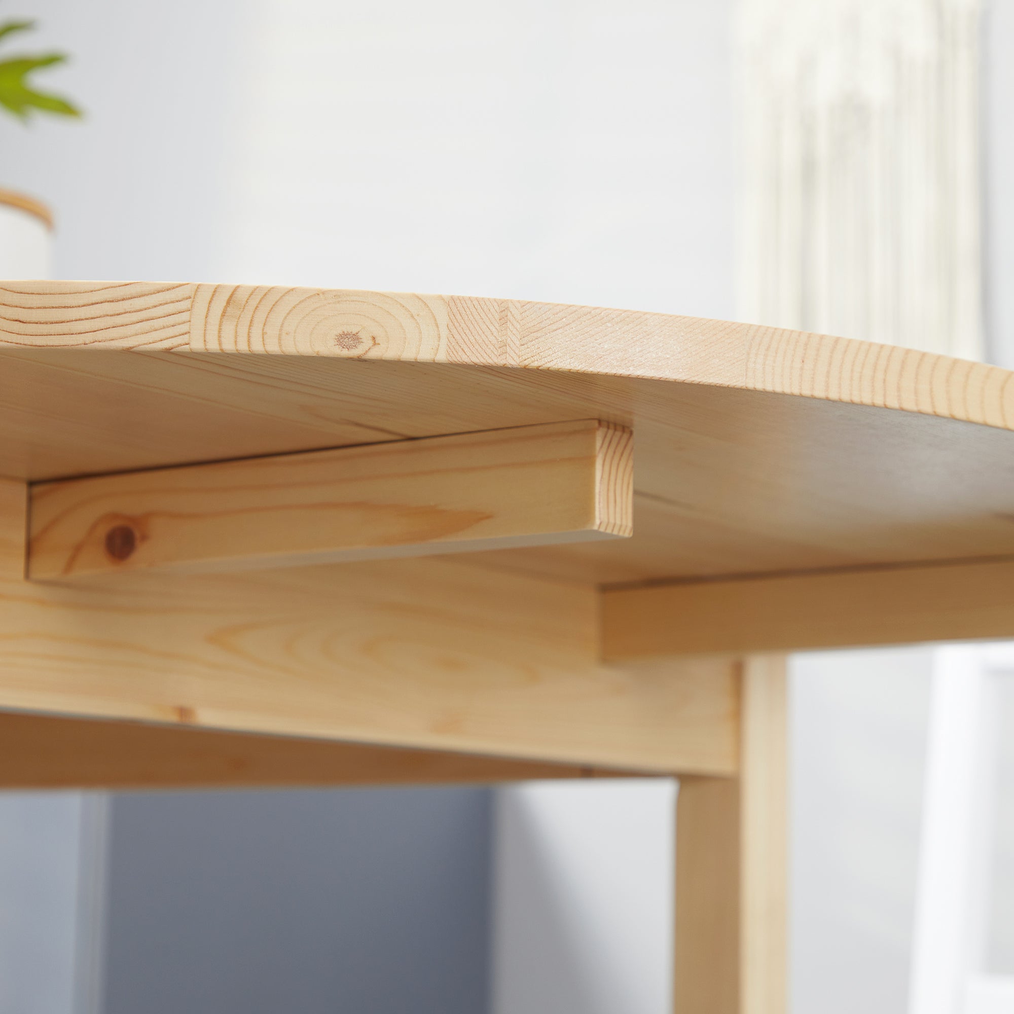Close-up of the natural pine tabletop edge, apron, and leg joinery