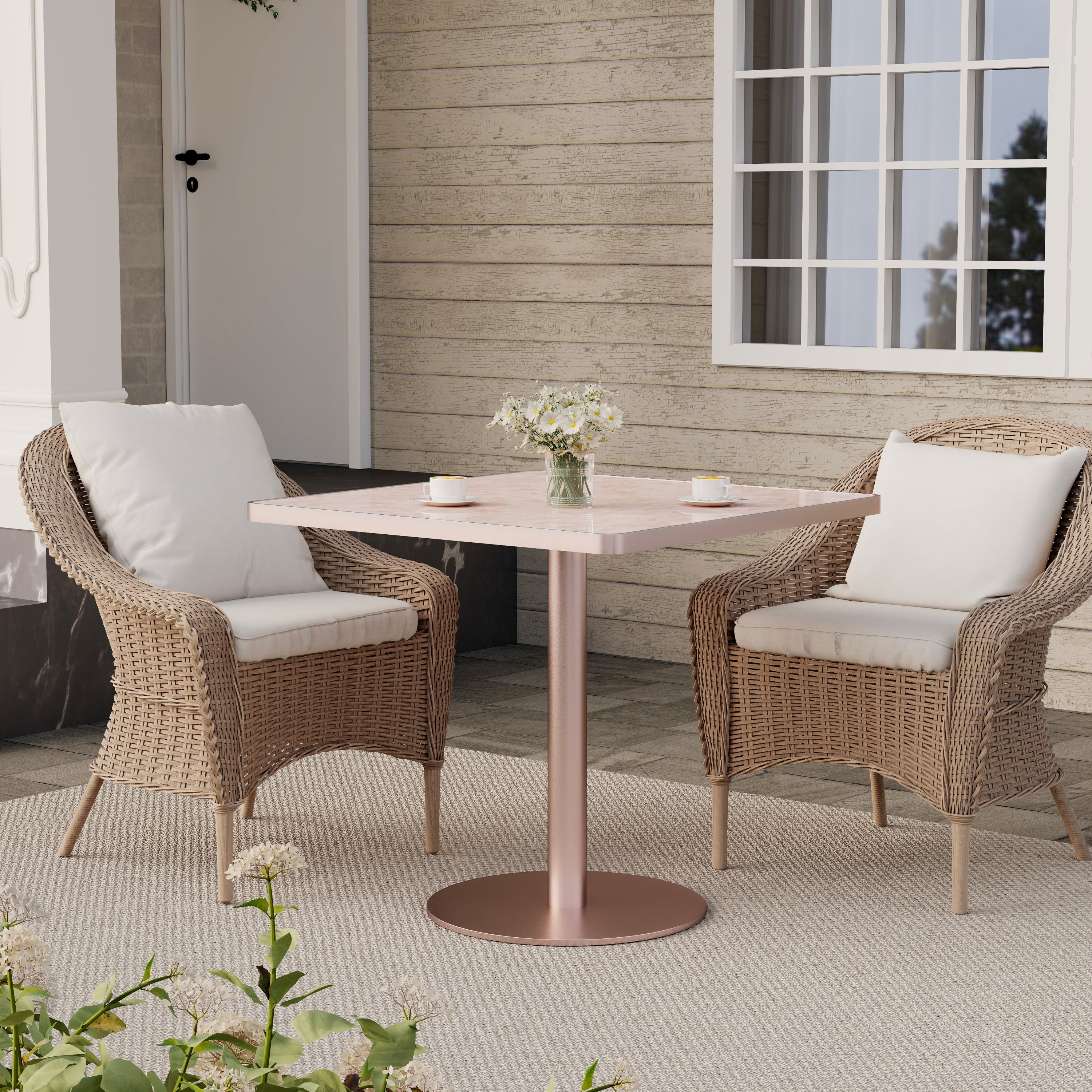 Pink onyx-look square dining table on a patio between two woven rattan armchairs