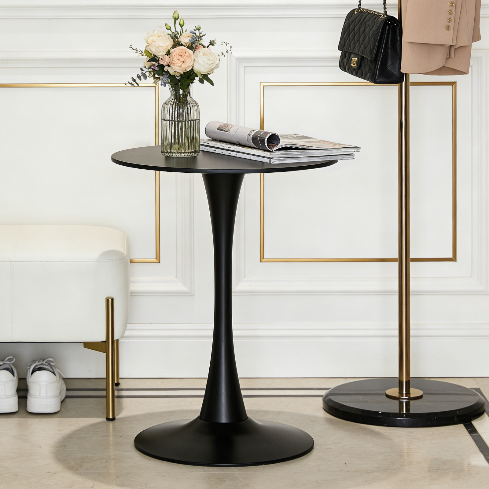Black round bistro table styled in an entryway with flowers and magazines