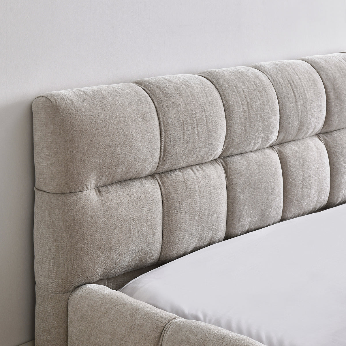 Close-up of the beige chenille channel-tufted headboard corner
