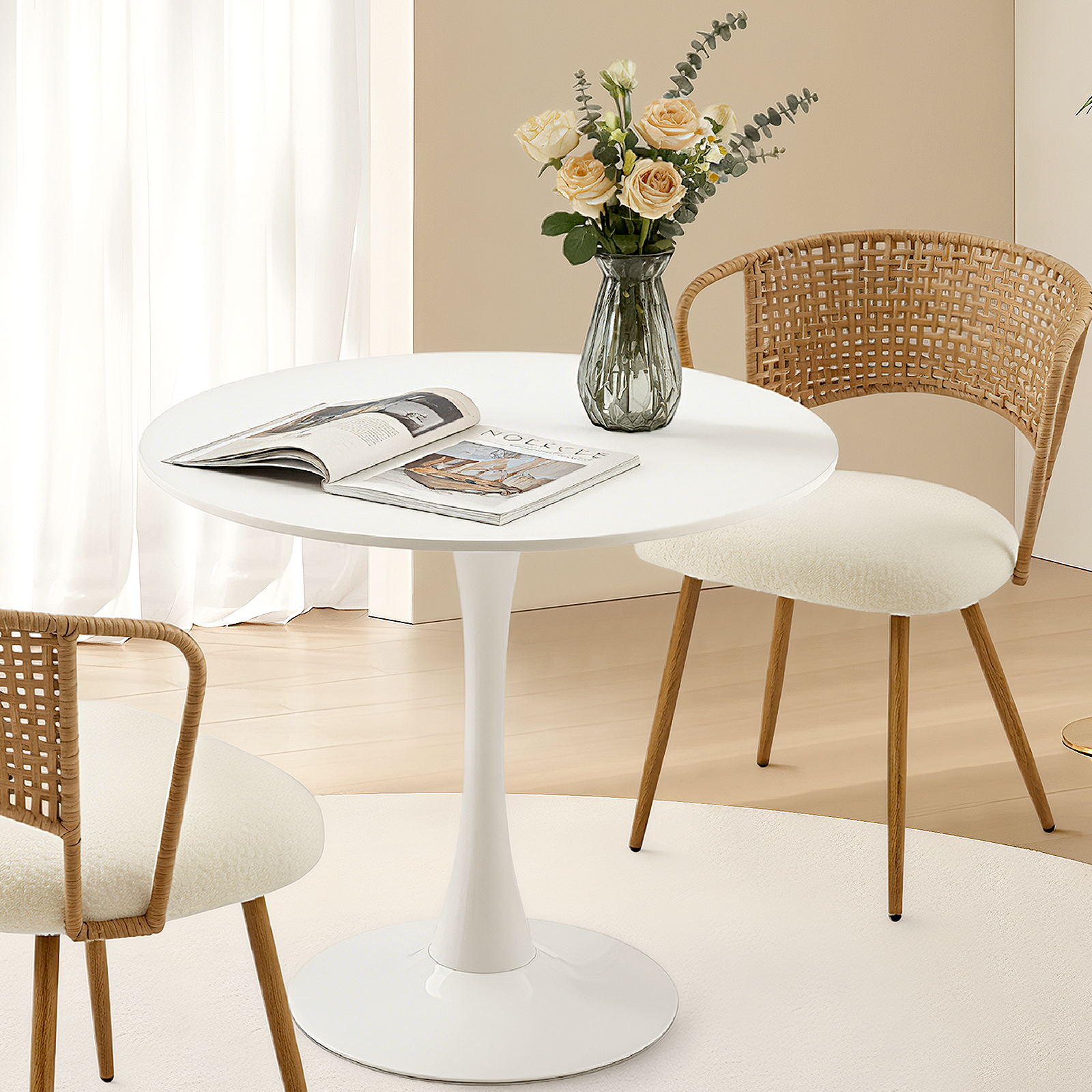 White round dining table with tulip base in a bright nook with a rattan and boucle chair