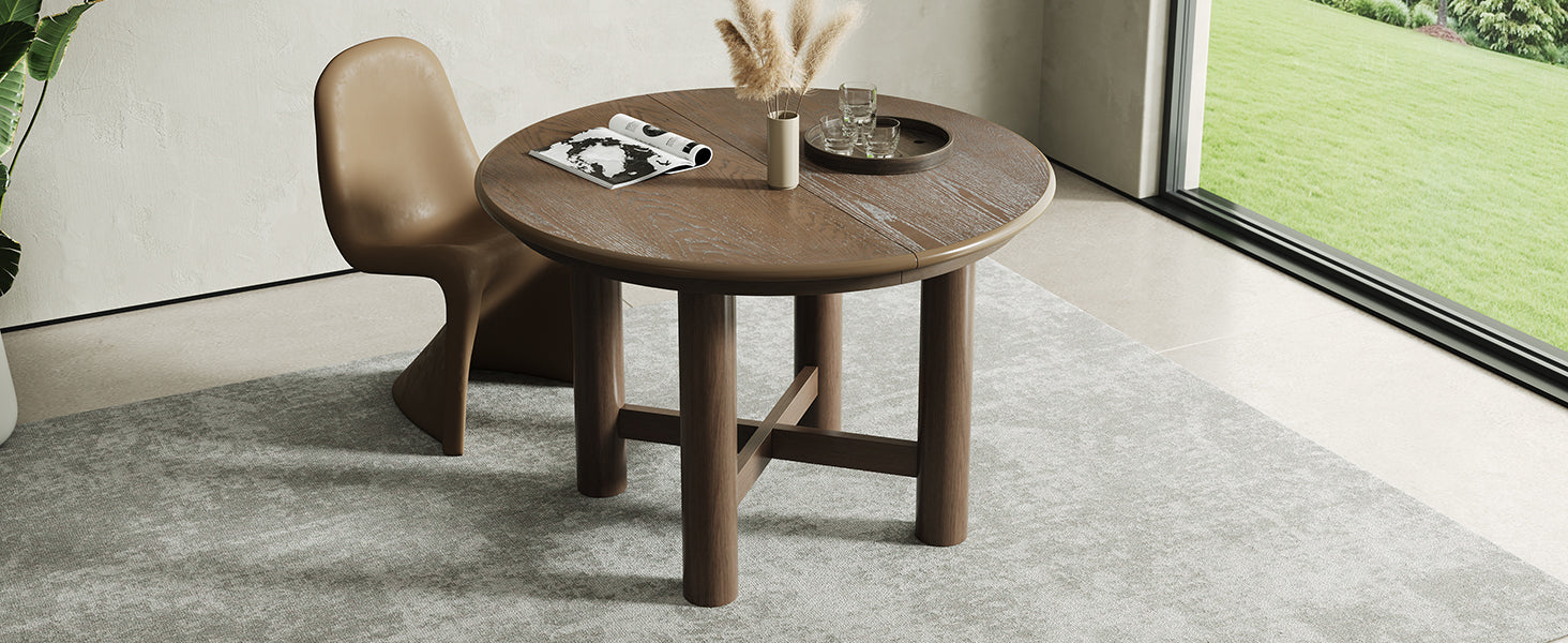 Round closed espresso oak table with two tan chairs beside a garden window