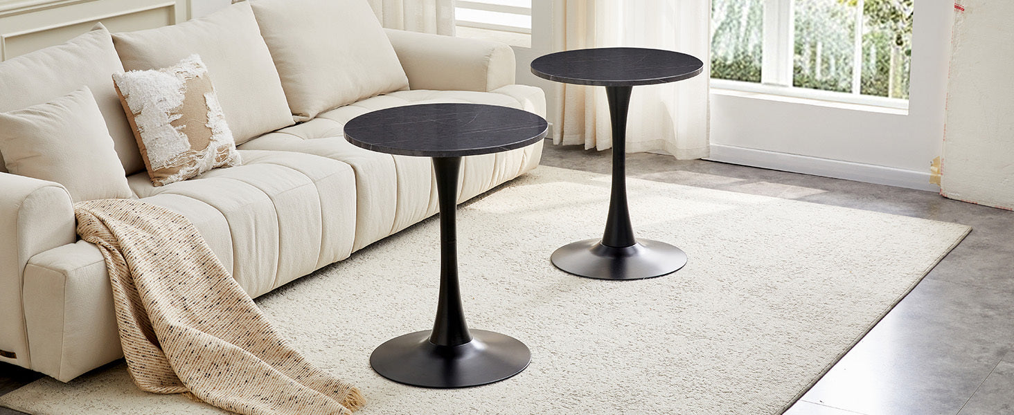 Two black marble-look bistro tables on a rug in a bright living room with an accent pillow