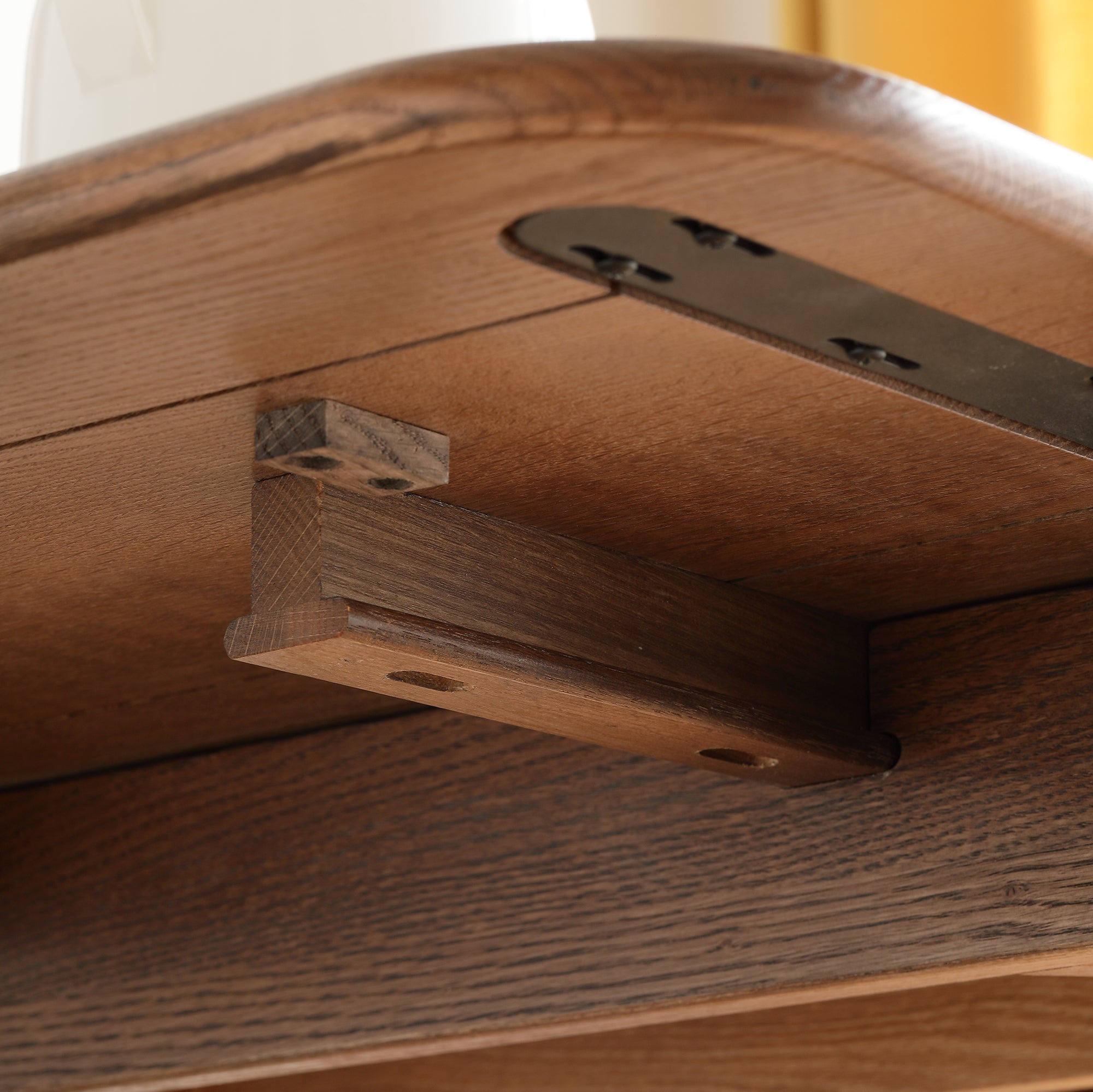 Close-up of the wood dowel extension joint and black hinge plate beneath the tabletop