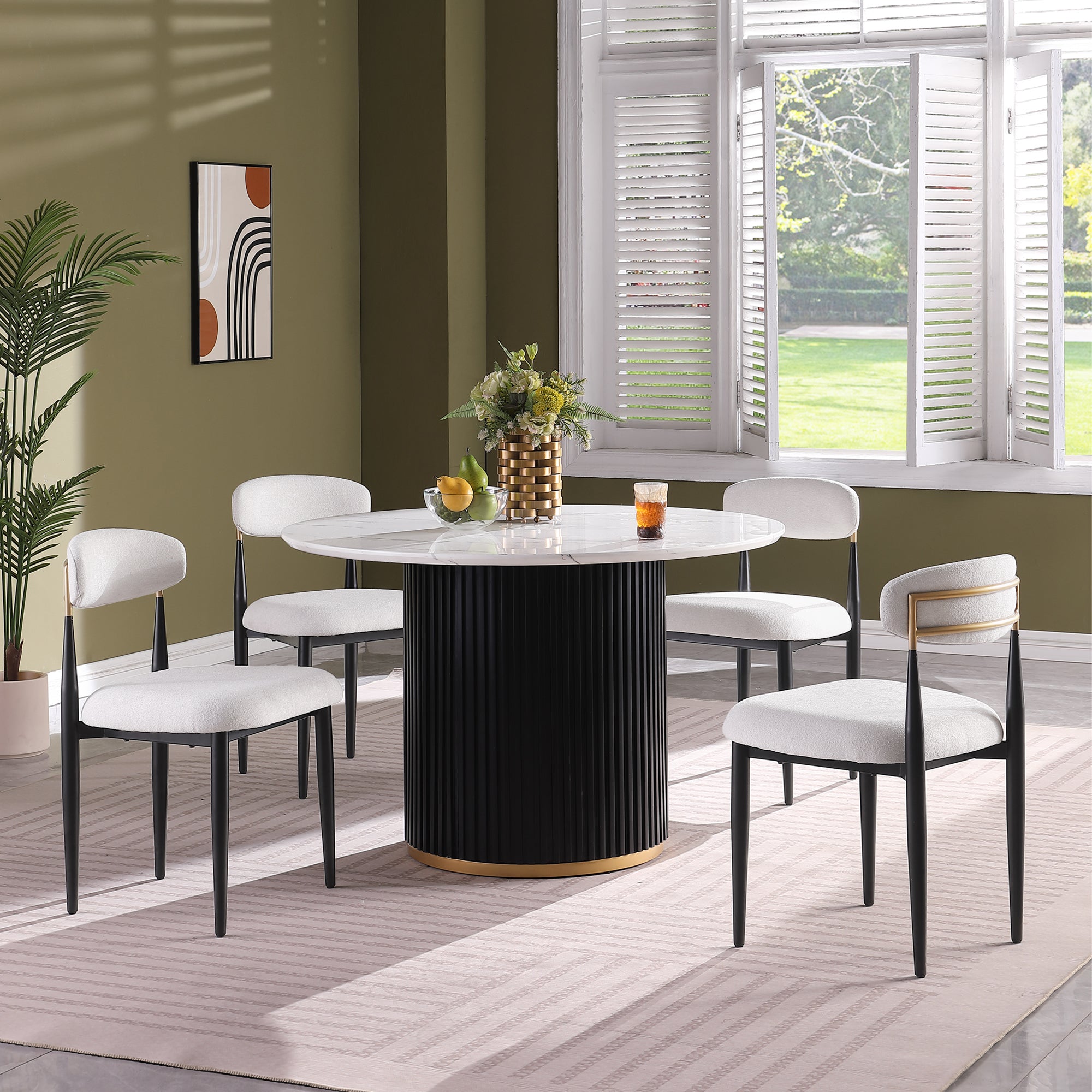 White faux marble round dining table with black fluted base and four white boucle chairs by a window