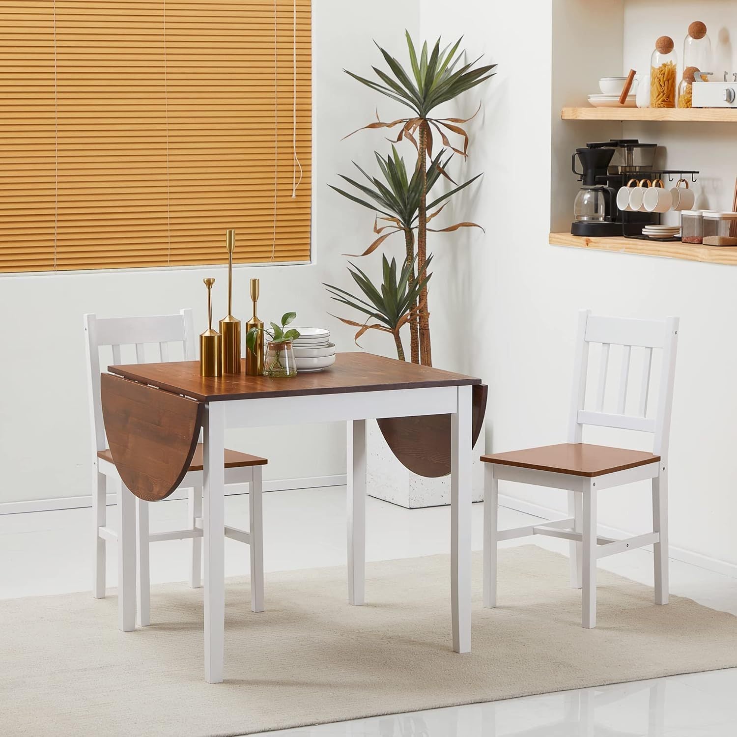 Brown pine folding drop-leaf dining table with white legs and two matching chairs in a styled kitchen