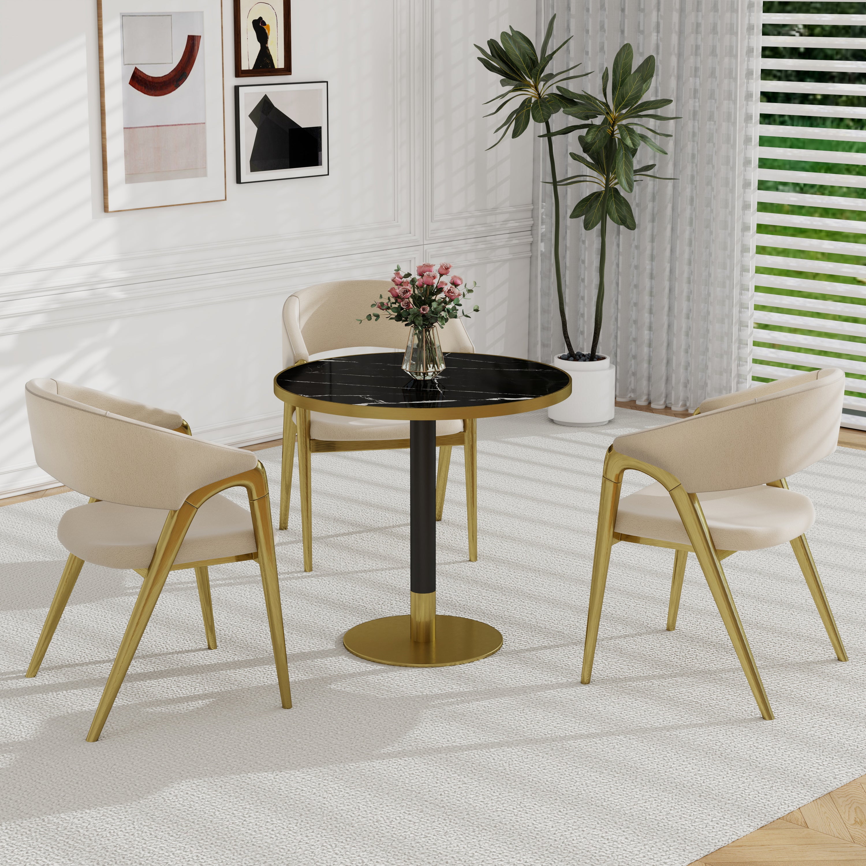Black and gold round dining table in a white living room with cream chairs, a rug, and pink roses