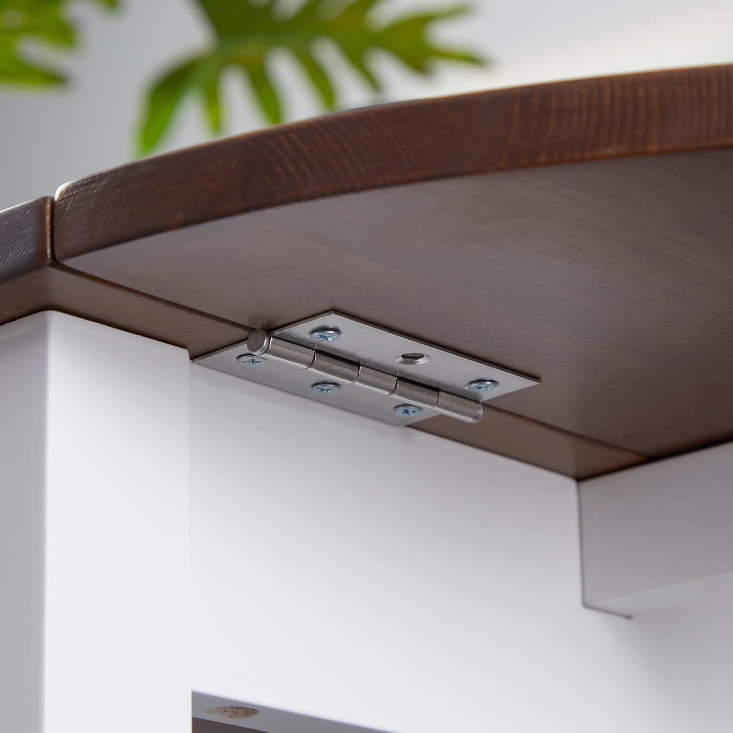 Close-up of the metal drop-leaf hinge screwed under the brown pine tabletop