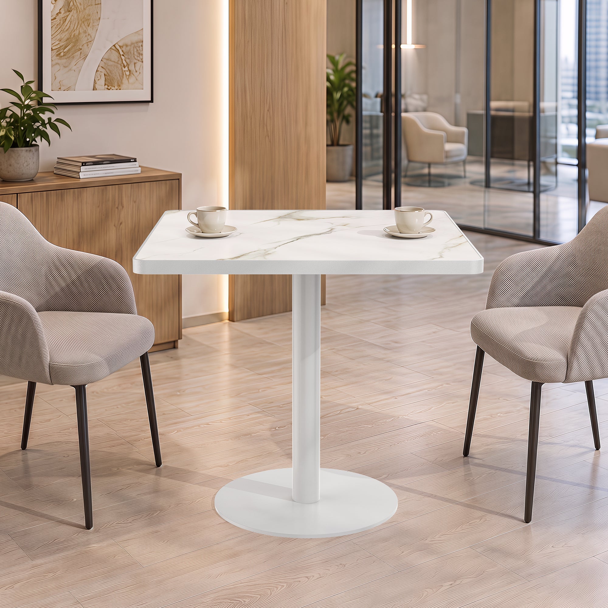 White stone square dining table styled in office lounge with two taupe chairs and coffee