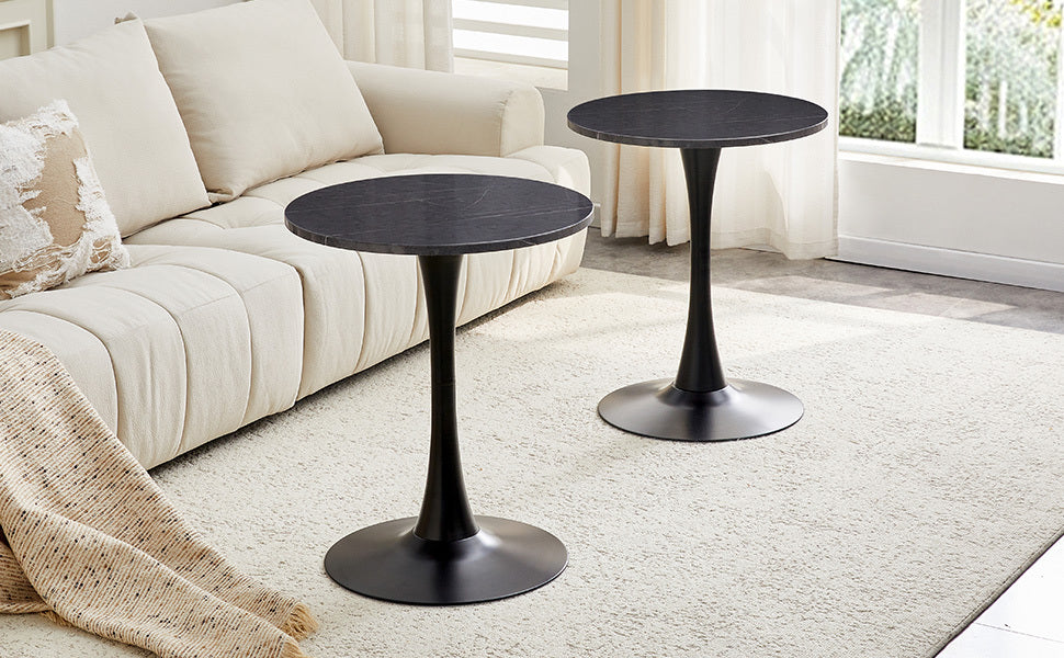 Two black marble-look bistro tables on a rug by a cream sofa with a draped throw blanket
