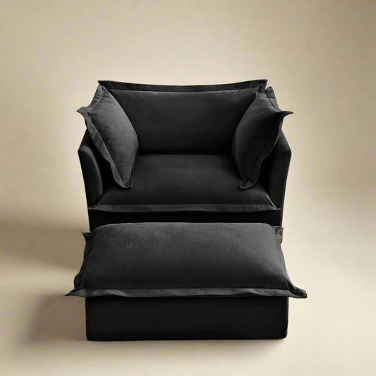 closeup shot of the fluffy chair in black chenille showing the plush seat backrest ottoman and pillows.