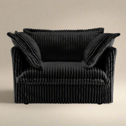 studio shot of the fluffy chair in black corduroy showing the rich texture of the upholstery plush pillows backrest and seat as well as the wide and deep seat cushion