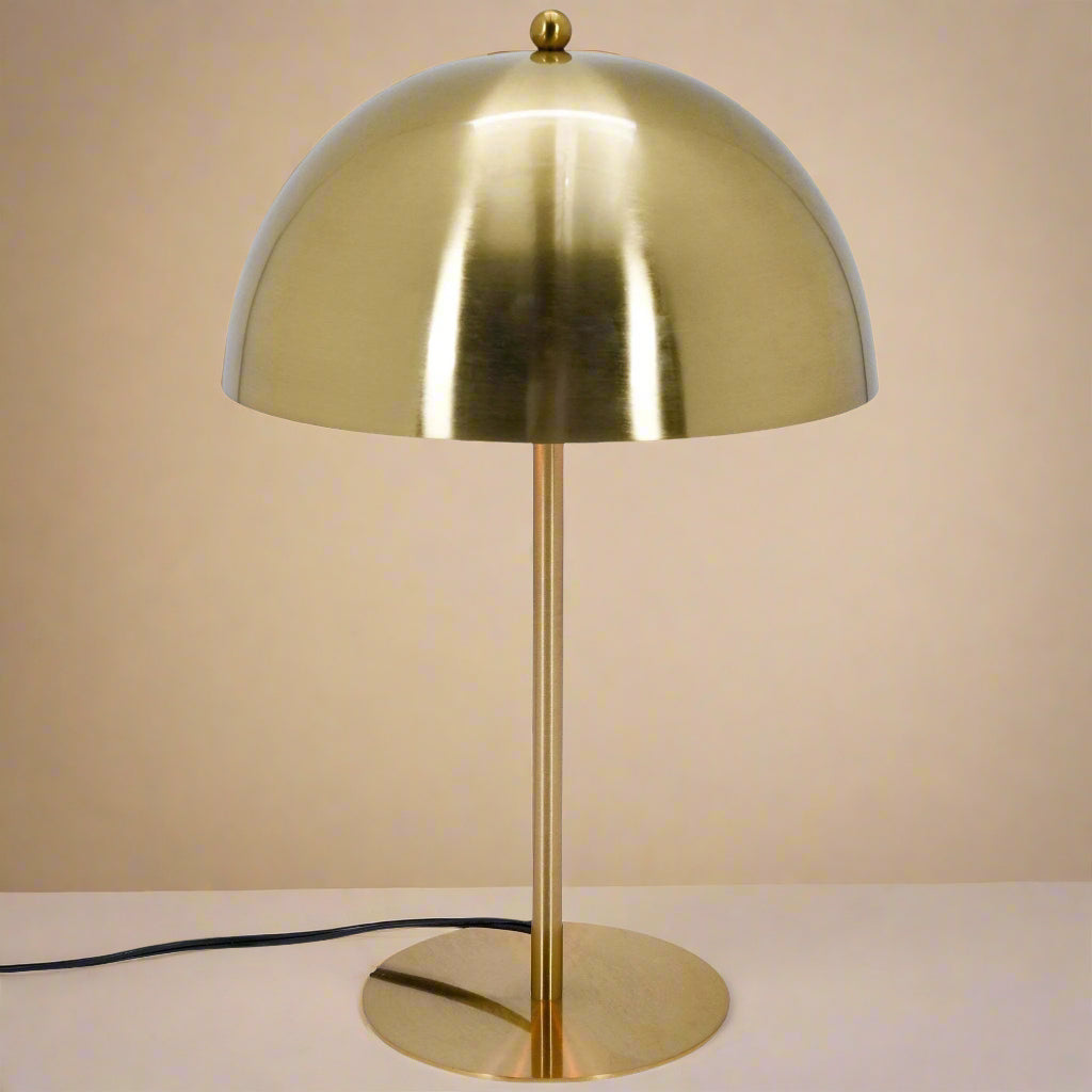 overview shot of a gold dome table lamp showing the reflective qualities of the dome and shade as well as the power cord