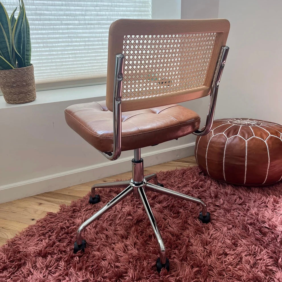 rear view showcasing the solid wood and rattan back rest on a mid century modern office chair with a brown vegan leather seat and a stainless steel frame