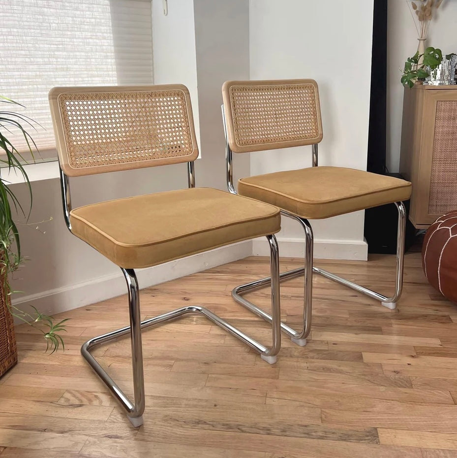yellow velvet mustard colored set of two dining chairs with cantilever design stainless steel frame and a seat back made of solid wood and rattan