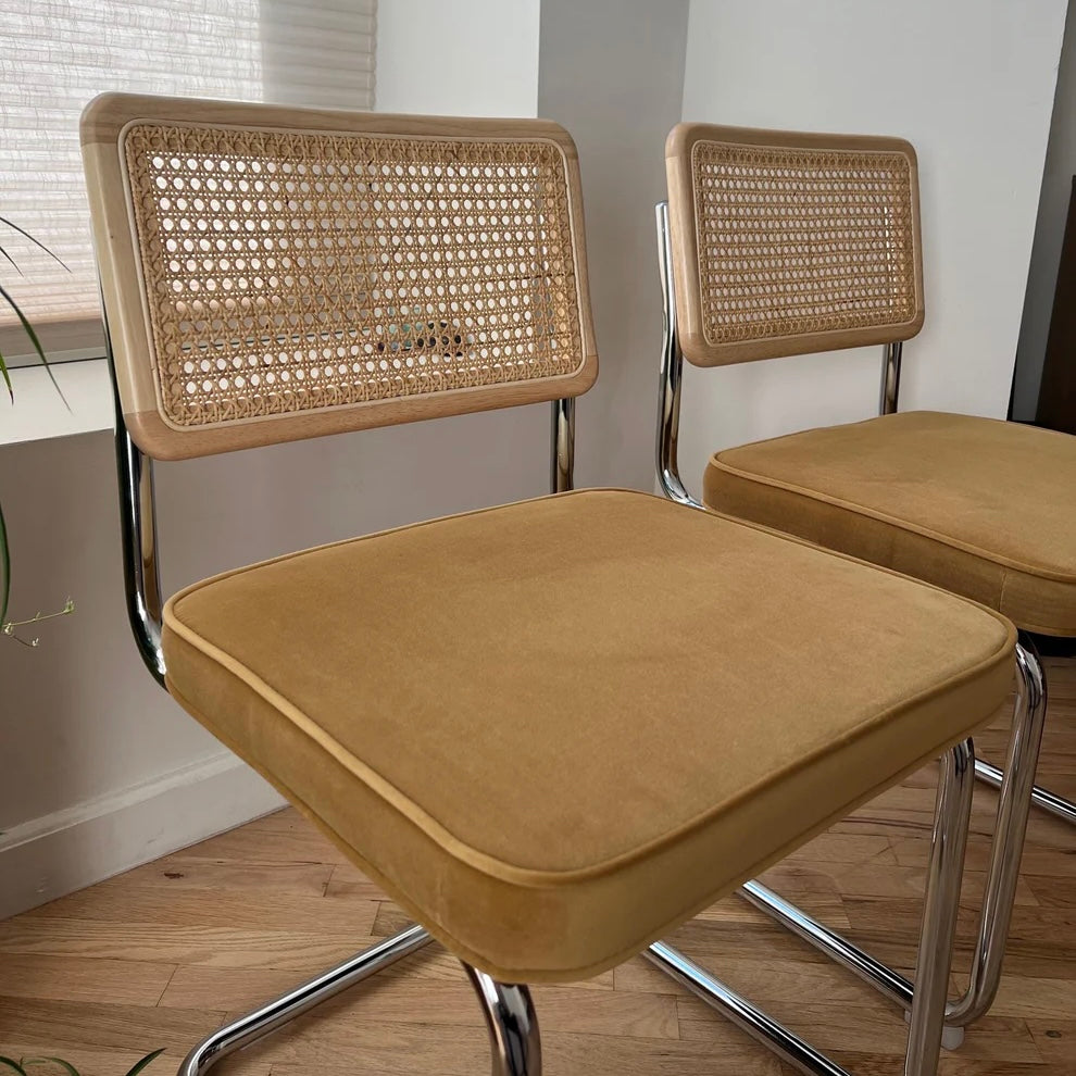 closeup of the yellow velvet seat cushion and the back rest made of solid wood and natural rattan on dining chairs