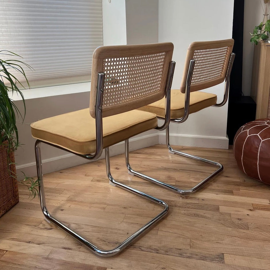 side rear of dining chairs featuring natural rattan stainless steel frames and solid wood back rests