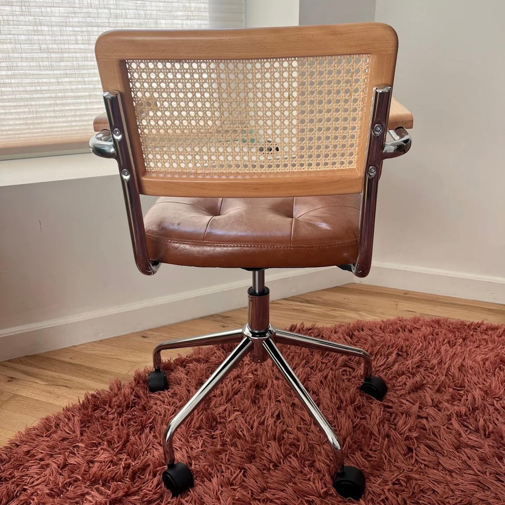 rear view of mcm office chair showing seat back and stainless steel frame as well as brown vegan leather seat and black wheels