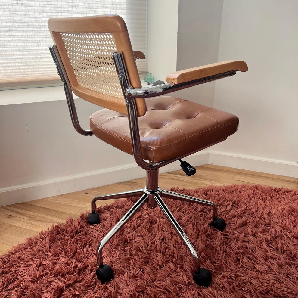 rear quarter view of mid century office chair with armrests showing hard wood and vegan leather seat as well as natural rattan back rest