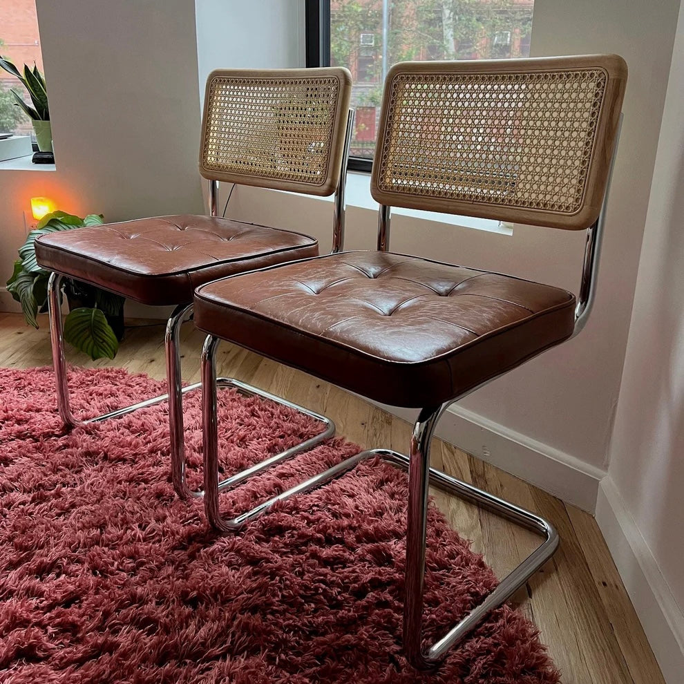 closeup of brown vegan leather seat on mid century modern cantilevered dining chairs with solid wood back rest with rattan accents