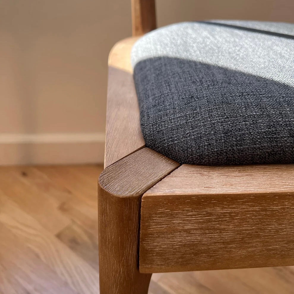 closeup of solid wood dining chair with navy upholstery featuring natural woodgrain detail