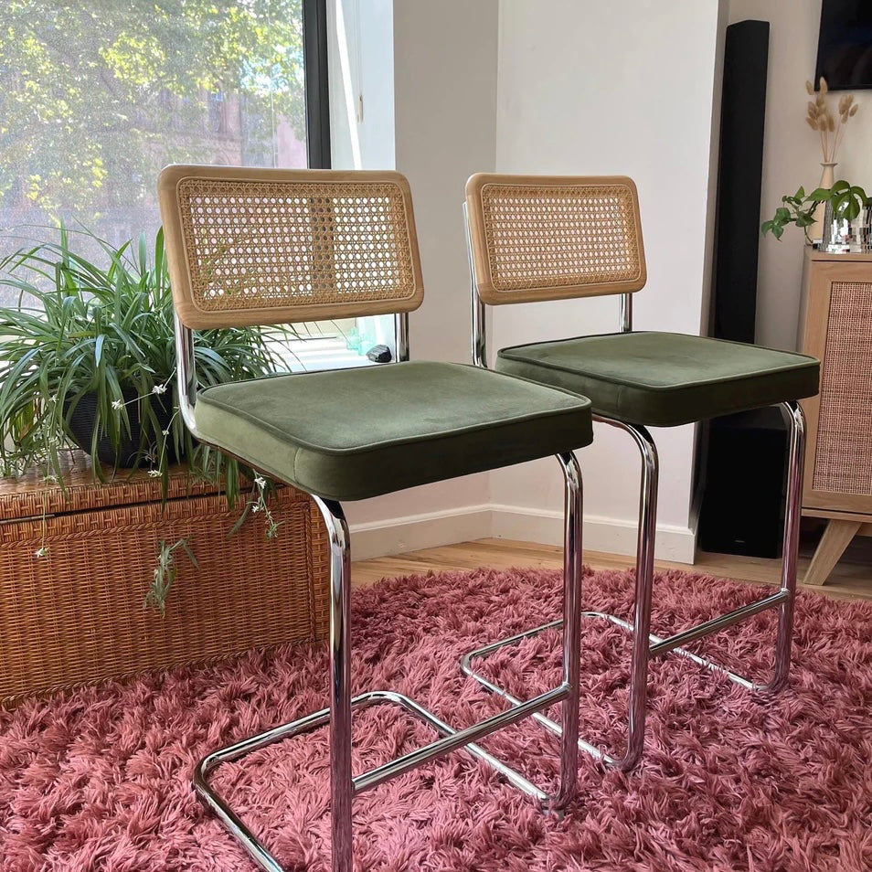 mid century modern interior with counter height bar stools that have green velvet seats and solid wood natural rattan backrests