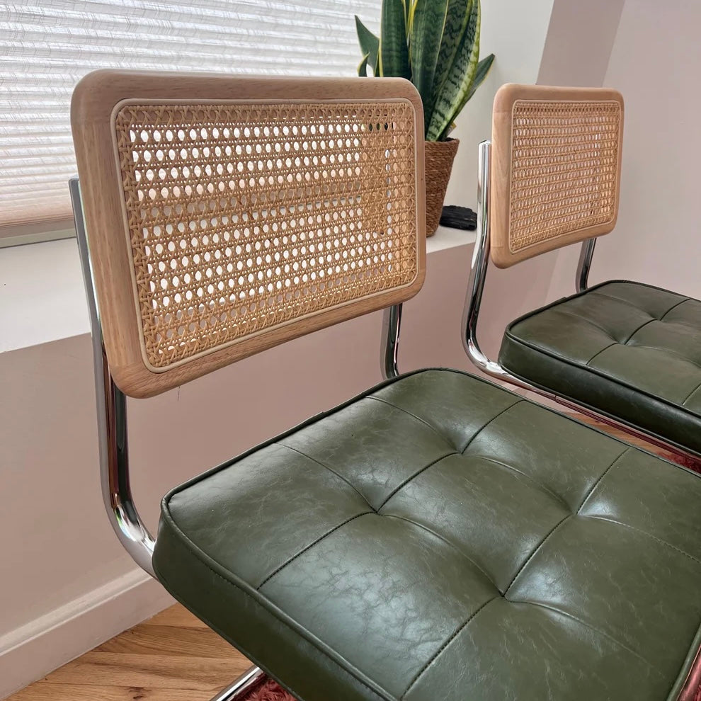 Close up of green vegan leather dining chairs and solid wood backrests with natural rattan