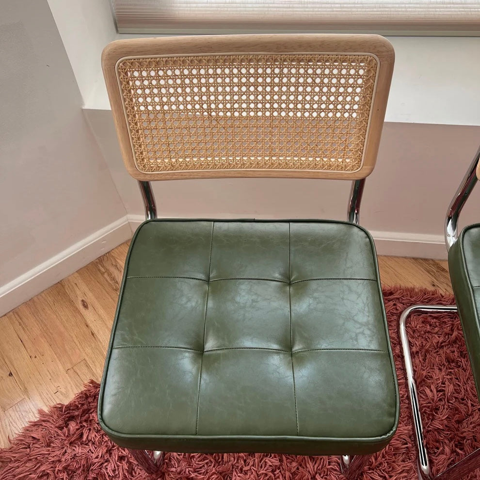 Overview of green vegan leather dining chair seat with solid wood backrest and rattan accents