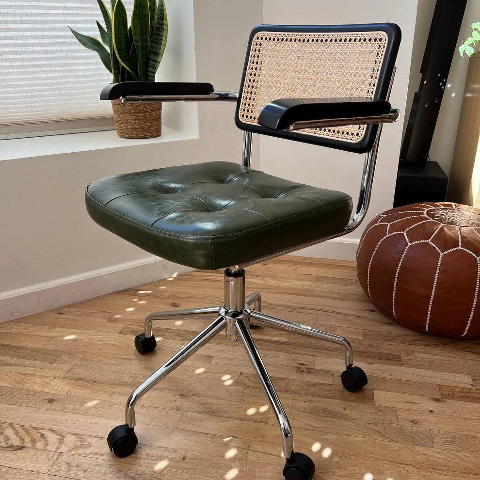 Midcentury modern office chair with a green vegan leather seat solid black stained wood armrests and a seatback with rattan accents