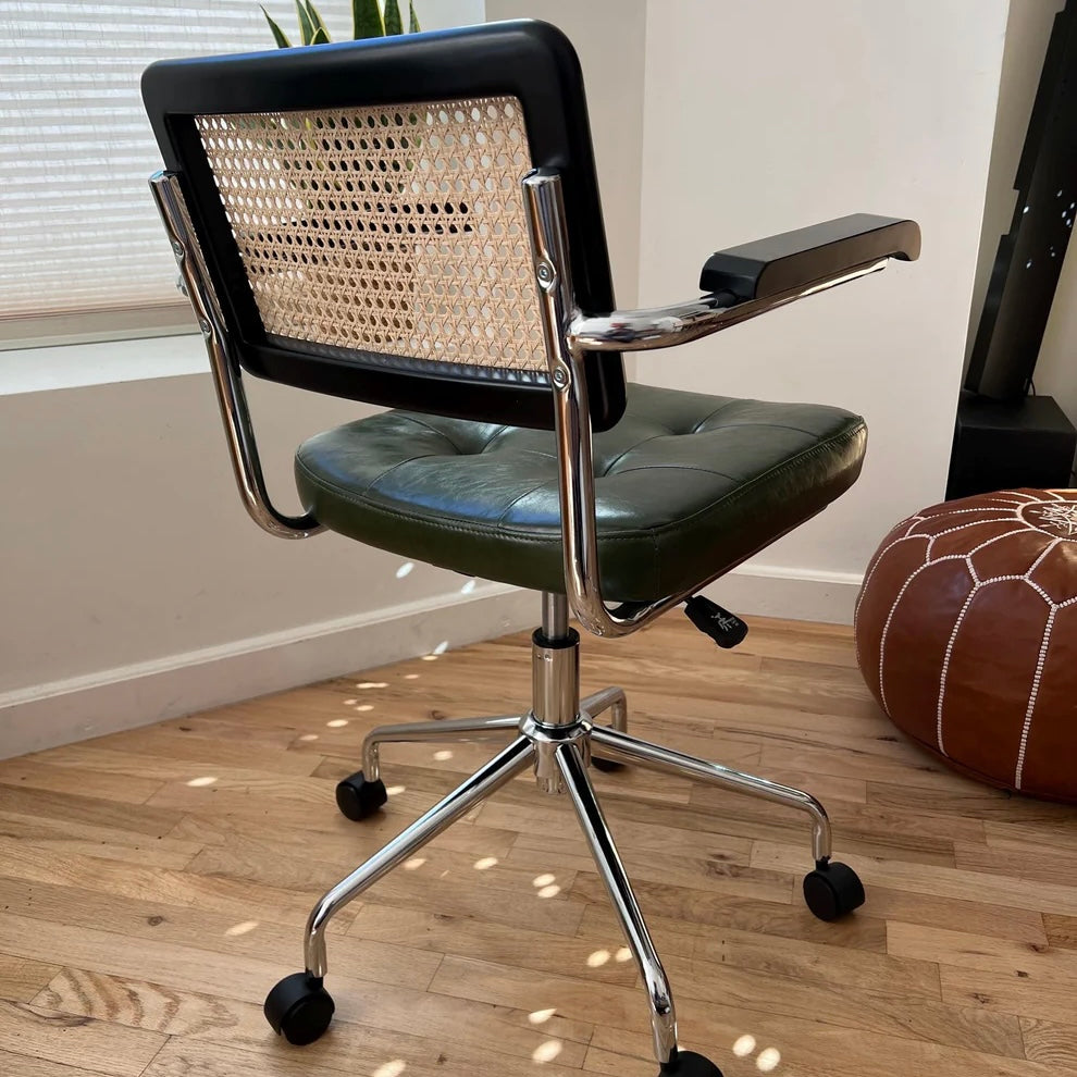 rear side view of black stained wood and natural rattan seat back on midcentury modern office chair with green vegan leather seat and stainless steel frame