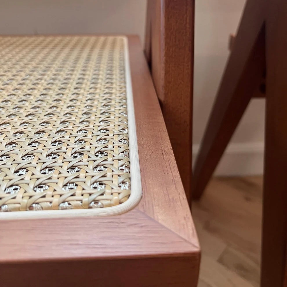 Closeup view of woodgrain patterning and natural rattan seat of walnut stain solid wood dining chair