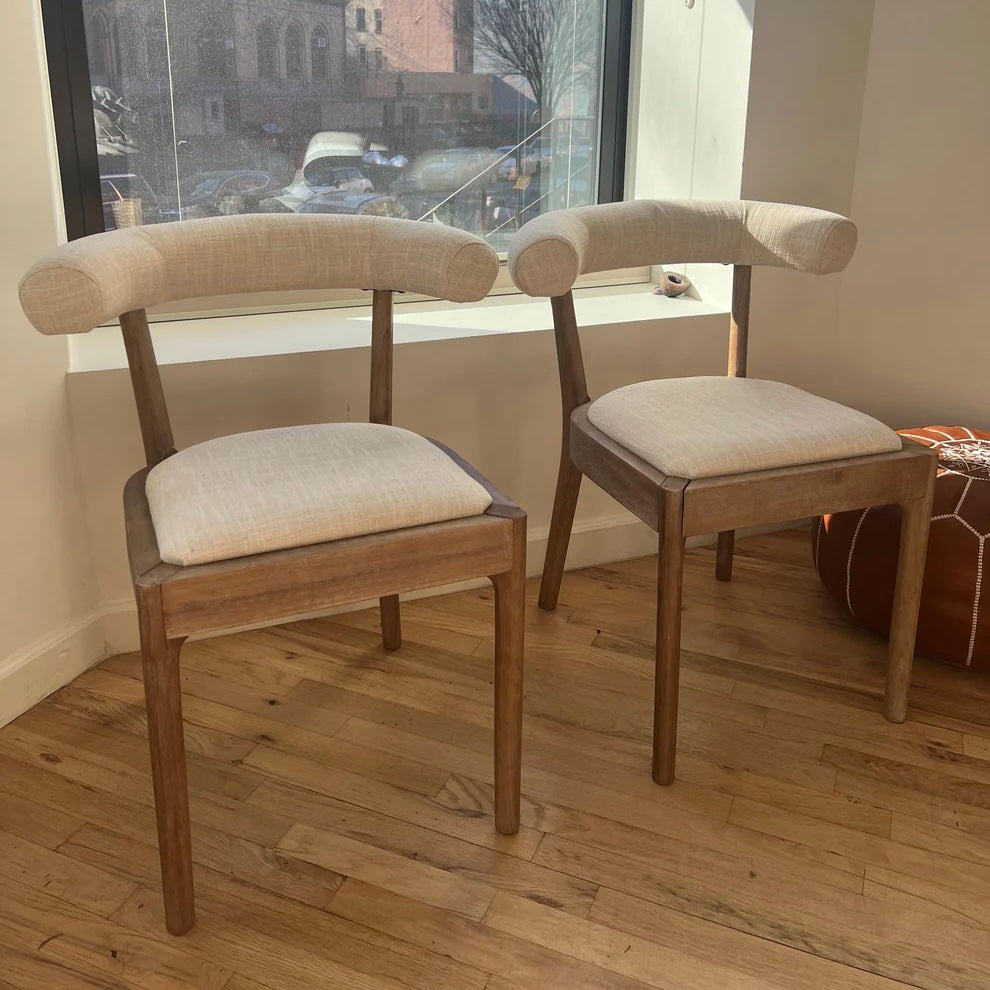 front view of solid wood dining chars with white linen upholstery and curved backrests