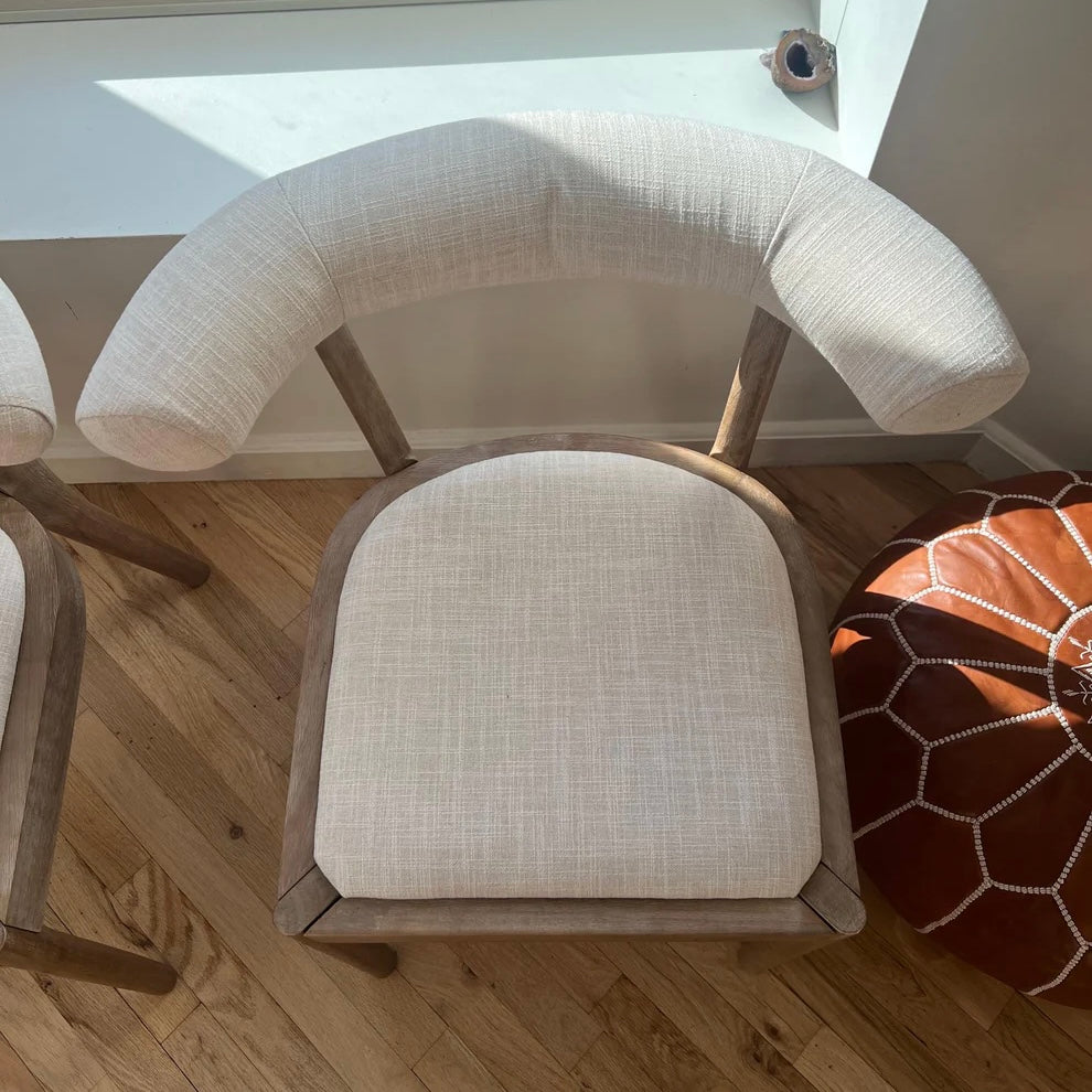 overview of white linen dining chair upholstery on a dining chair with solid wood legs