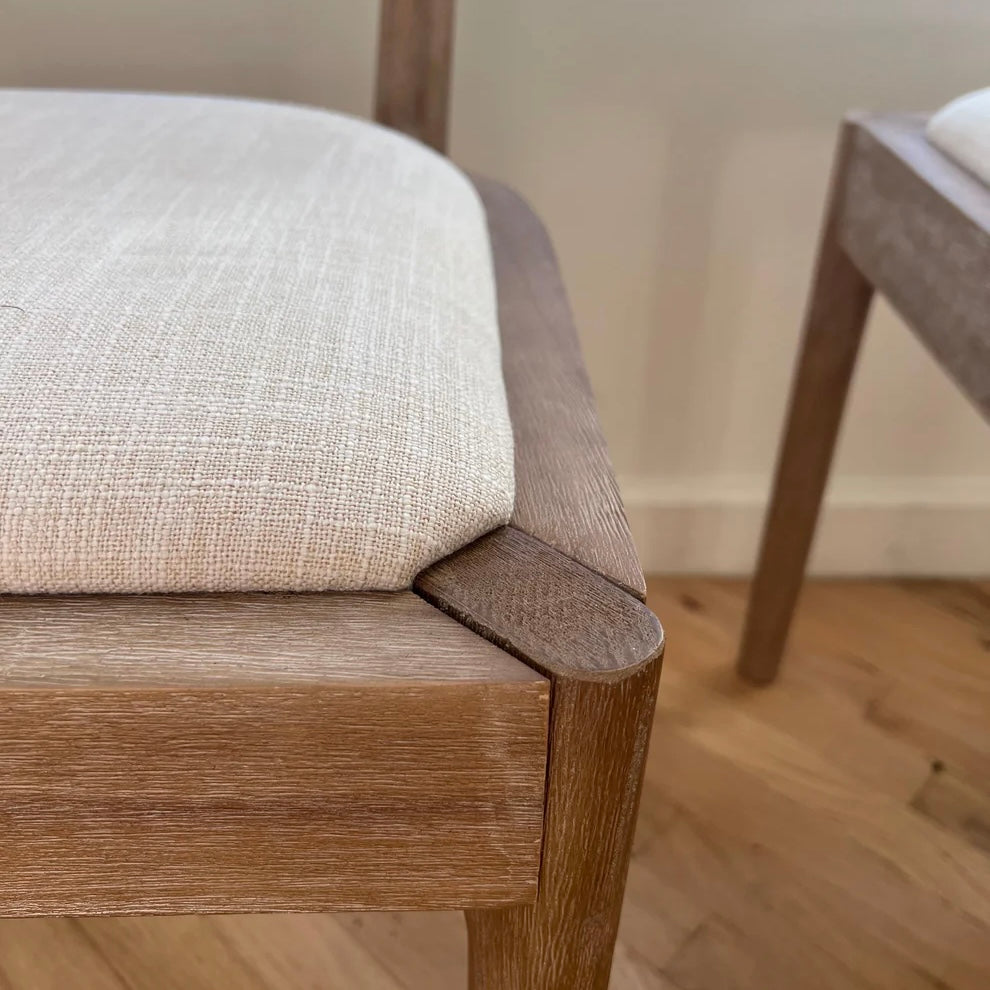 close up of woodgrain pattern on solid wood dining chair with white upholstery seat