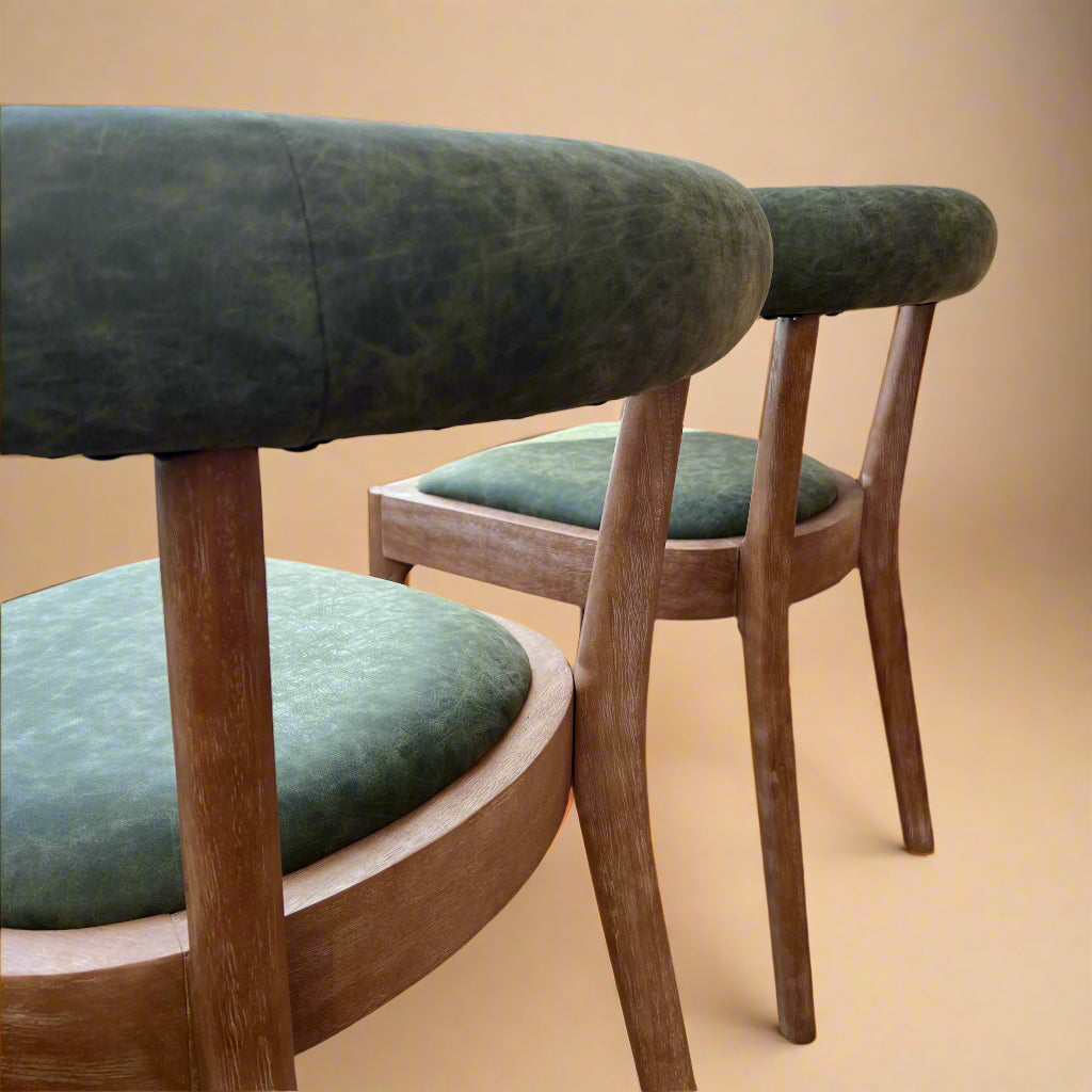 rear view of solid wood dining chairs with green vegan leather seats and curved backrests