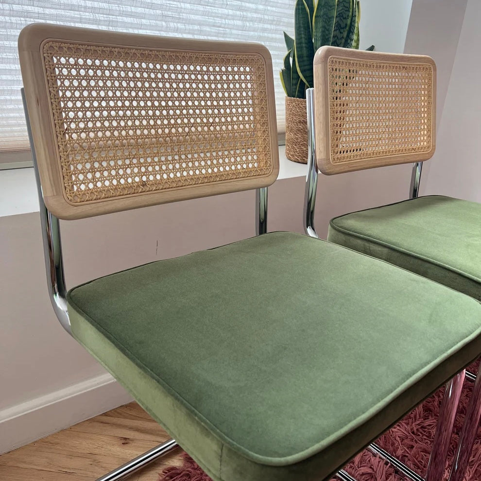 close up of green velvet seat on mid century modern dining chairs with solid wood back rest and rattan accents