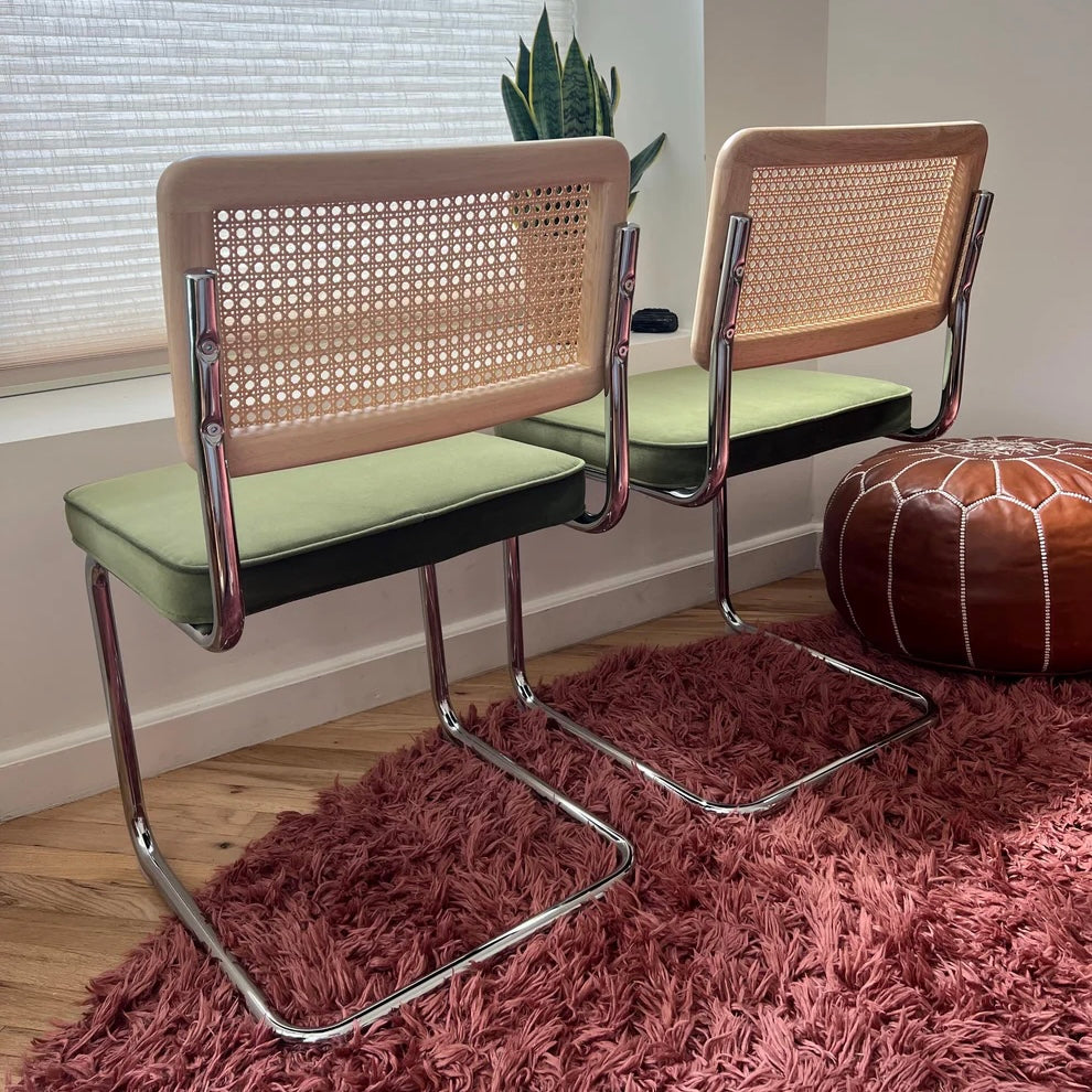 Rear view of mid-century modern cantilevered dining chairs with solid wood and natural rattan backrests and stainless steel frames