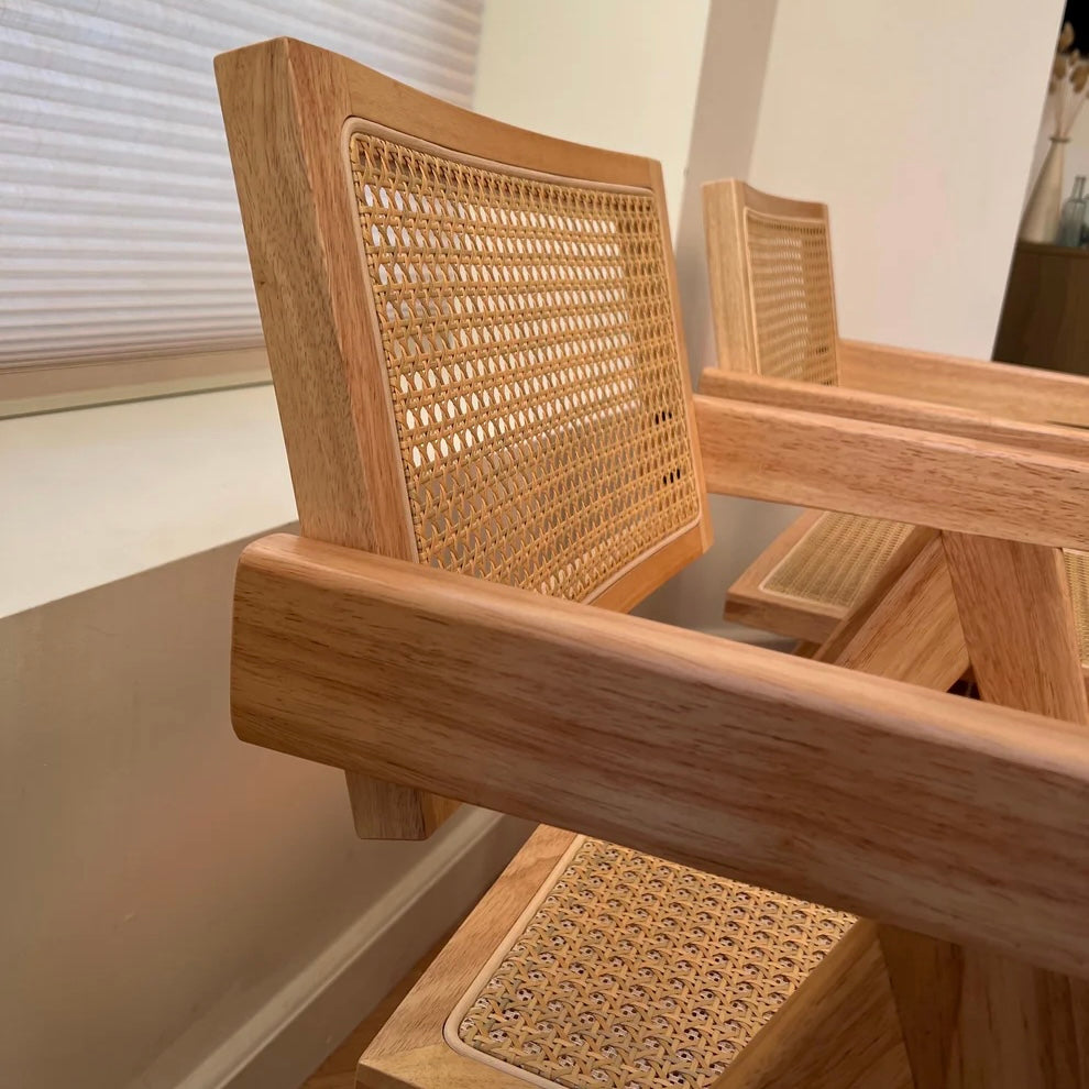 Closeup of woodgrain patterns on solid wood dining chairs with natural rattan and stitching visible