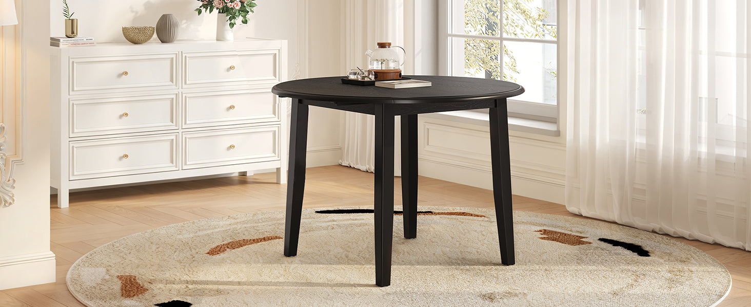 Angled styled room view of the black round table with a drop leaf folded
