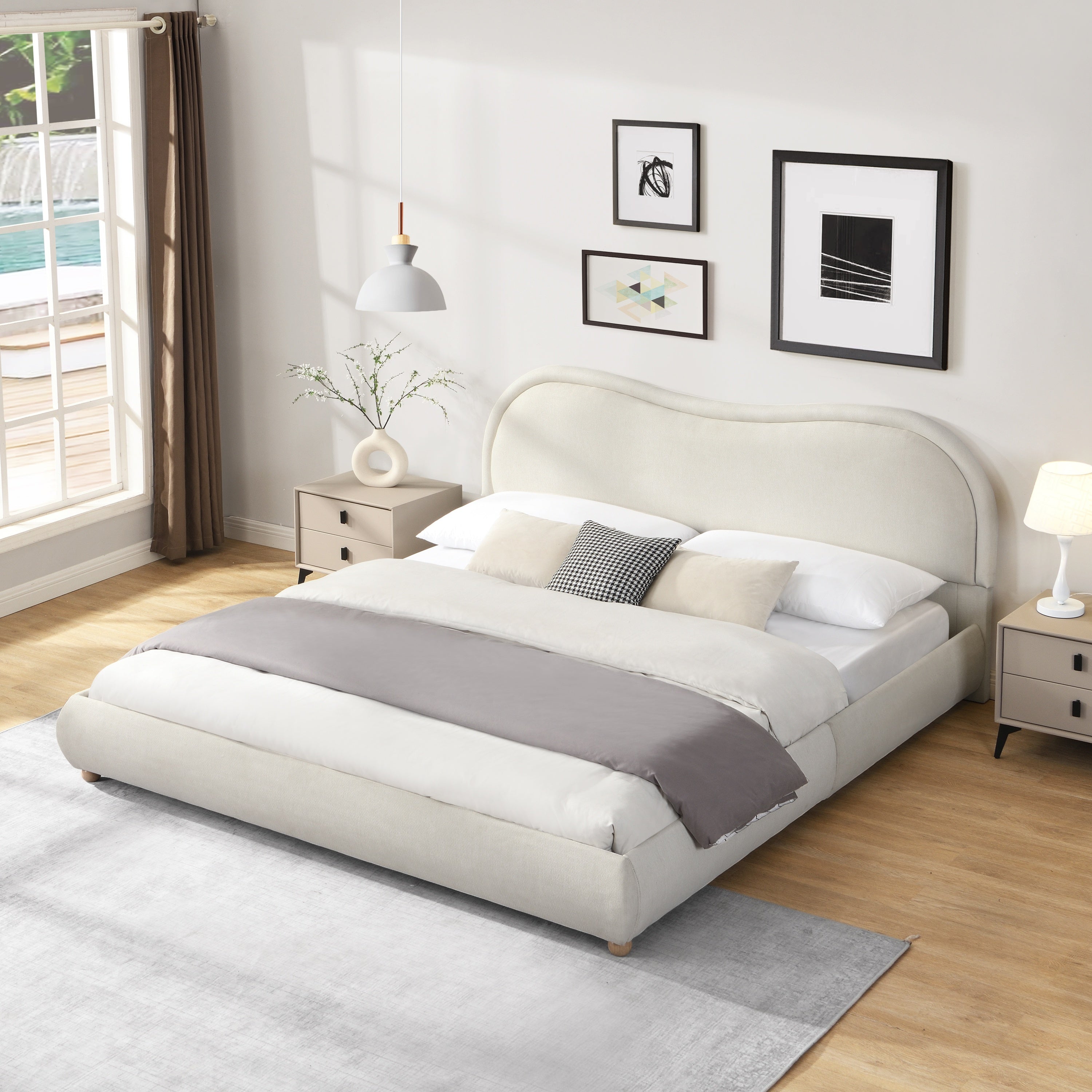 Beige king platform bed in a sunlit bedroom with layered gray and white bedding